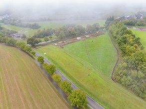 Aerial view of a foggy rural landscape with fields and roads, construction of a PV open-air system,