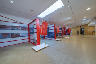 Modern exhibition room with red information stands and bright lighting in a minimalistic design,