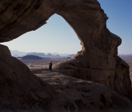 Bedouin under a natural rock bridge, Wadi Rum, Jordan