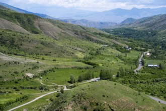 Green fields and rolling hills with roads leading through the area, under clear skies, countryside