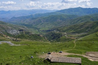 Mountains with isolated vehicles in a meadow, peaceful natural landscape under blue sky, view from