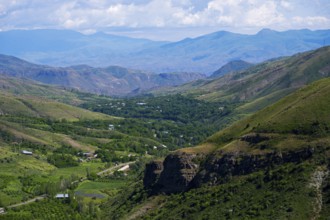 Extensive valley surrounded by green mountains, scattered villages visible under blue skies,
