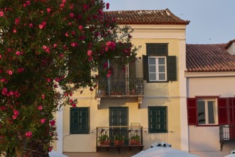 Old town of Nauplion, Traditional house with red shutters and flowers in evening sunlight,