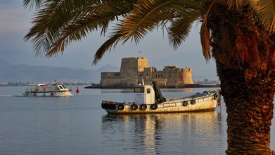Bourtzi island fortress, port of Nauplion, boats near an old fortress on an island, framed by palm