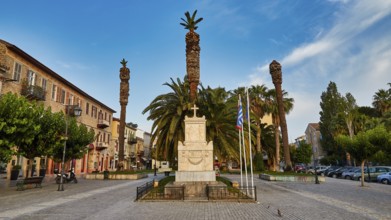 Old town of Nauplion, monumental town square with palm trees and a monument under a clear sky,