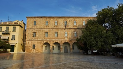 Old town of Nauplion, historic brick building with round arches in front of a paved square with