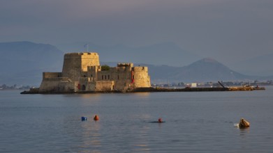 Bourtzi island fortress, old fortress on an island in the calm sea, surrounded by buoys and