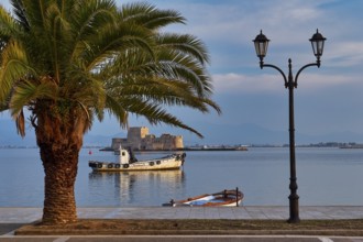 Bourtzi island fortress, port of Nauplion, palm tree and lanterns at the seaport with a view of a