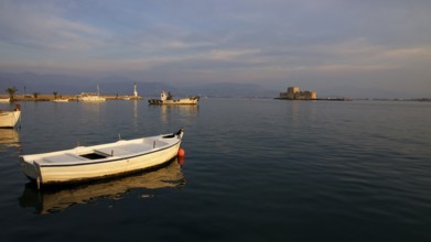 Nauplion harbour, Bourtzi island fortress, white boats on the calm sea at dusk with a fortress in