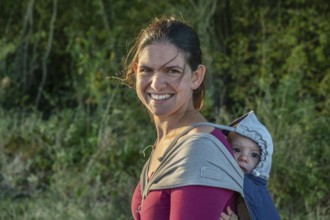 Young mother carrying her baby in a shawl on her back, Othenstorf, Mecklenburg-Western Pomerania,