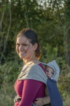 Young mother carrying her baby in a shawl on her back, Othenstorf, Mecklenburg-Western Pomerania,
