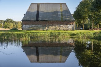 Old poultry house on an estate from 1923, reflected in the pond, Othenstorf, Mecklenburg-Western