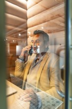 Man talking on smartphone, working in a contemporary soundproof office pod, representing