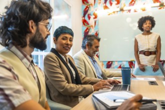 Diverse group of business colleagues meeting and collaborating in a modern office, sharing ideas