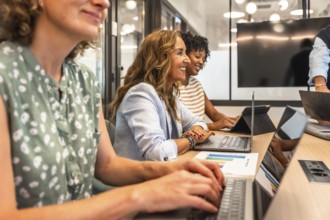 Diverse group of smiling businesswomen collaborating and engaging in productive work during a team