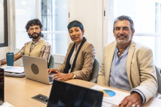 Diverse business colleagues working together around a table in a bright coworking office, smiling