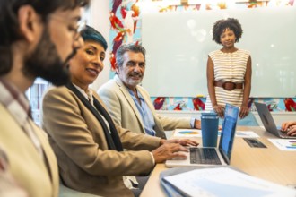 Diverse business colleagues holding a meeting or presentation, working and smiling in a colorful