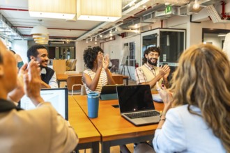 Diverse business colleagues celebrating success and achievement during a corporate meeting, showing