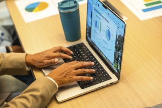 Person working on a laptop, hands typing on the keyboard, with a monthly performance review screen