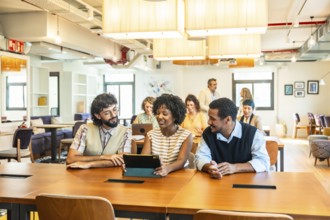 Diverse business colleagues collaborating around a tablet in a modern open plan office,