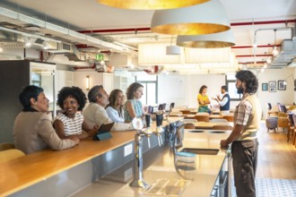 Diverse business colleagues enjoying a casual conversation at the counter of a modern coworking