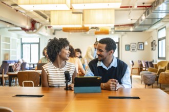 Two diverse colleagues collaborating and discussing ideas while recording a podcast with a