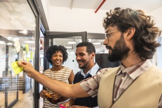 Diverse business colleagues collaborating and developing strategies, sticking colorful notes with