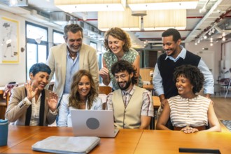 Diverse business colleagues collaborating and smiling during a video call on a laptop in a modern