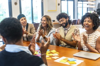 Diverse business colleagues celebrating successful ideas and achievements, clapping and smiling