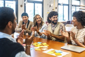 Coworkers clapping and smiling during a collaborative office meeting, showcasing teamwork,