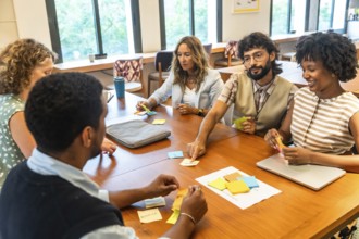 Diverse business team collaborating around a wooden conference table, brainstorming with colorful