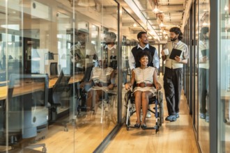 Diverse business team smiling and moving together through a contemporary glass walled office
