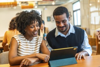 Diverse young business colleagues are enjoying a teamwork moment, looking at a digital tablet