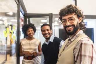 Group of diverse colleagues standing together and smiling in a contemporary coworking office,