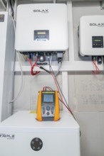 PVCheck PRO in front of installed Solax devices with red cable connections