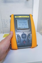 A person holds the PVCheck PRO device with an active display