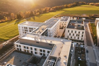 Modern buildings and nature under a glowing sunset sky, new hospital, Calw Health Campus, Black