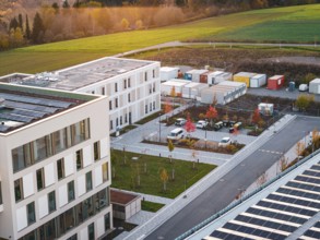 Campus with office buildings and colorful autumn trees next to a container area, new hospital, Calw