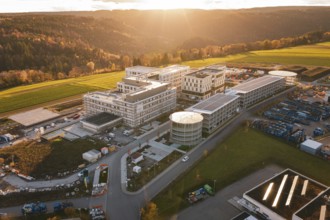 Modern buildings surrounded by fields and hills at sunset, aerial view, new hospital, Calw health