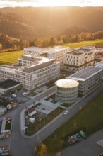 Modern buildings in rural landscape with forests and fields at sunset, aerial view, new hospital,