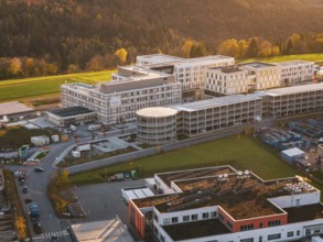 Building complex surrounded by autumn landscape and industrial area, aerial view at sunset, new