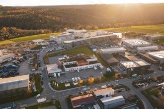 Large building complex with surrounding industrial areas in autumn landscape at sunset, new