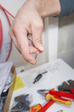 Electrician holds a plug, tools and packaging in the background