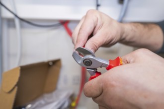 Close-up of hands cutting cable with pliers