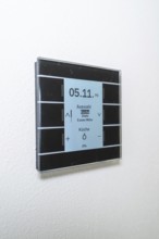 A modern switch on the wall with a blue display