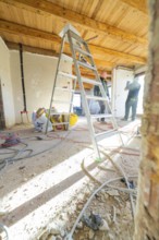 A ladder and tools on a construction site with a wooden ceiling