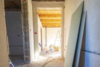 Construction situation in a room with unfinished walls and ceiling. Daylight is pouring in