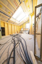 Conversion in an attic with visible wiring and incoming daylight through skylights