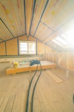 Renovation work in the attic with large windows and open insulation elements under the roof