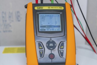 Measuring device with cables shows various electrical measurements on a display
